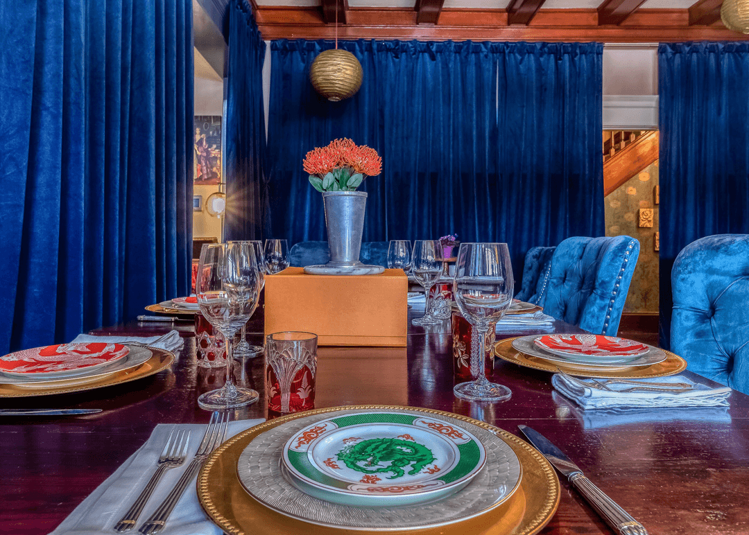 Formally set dining table surrounded by royal blue curtains