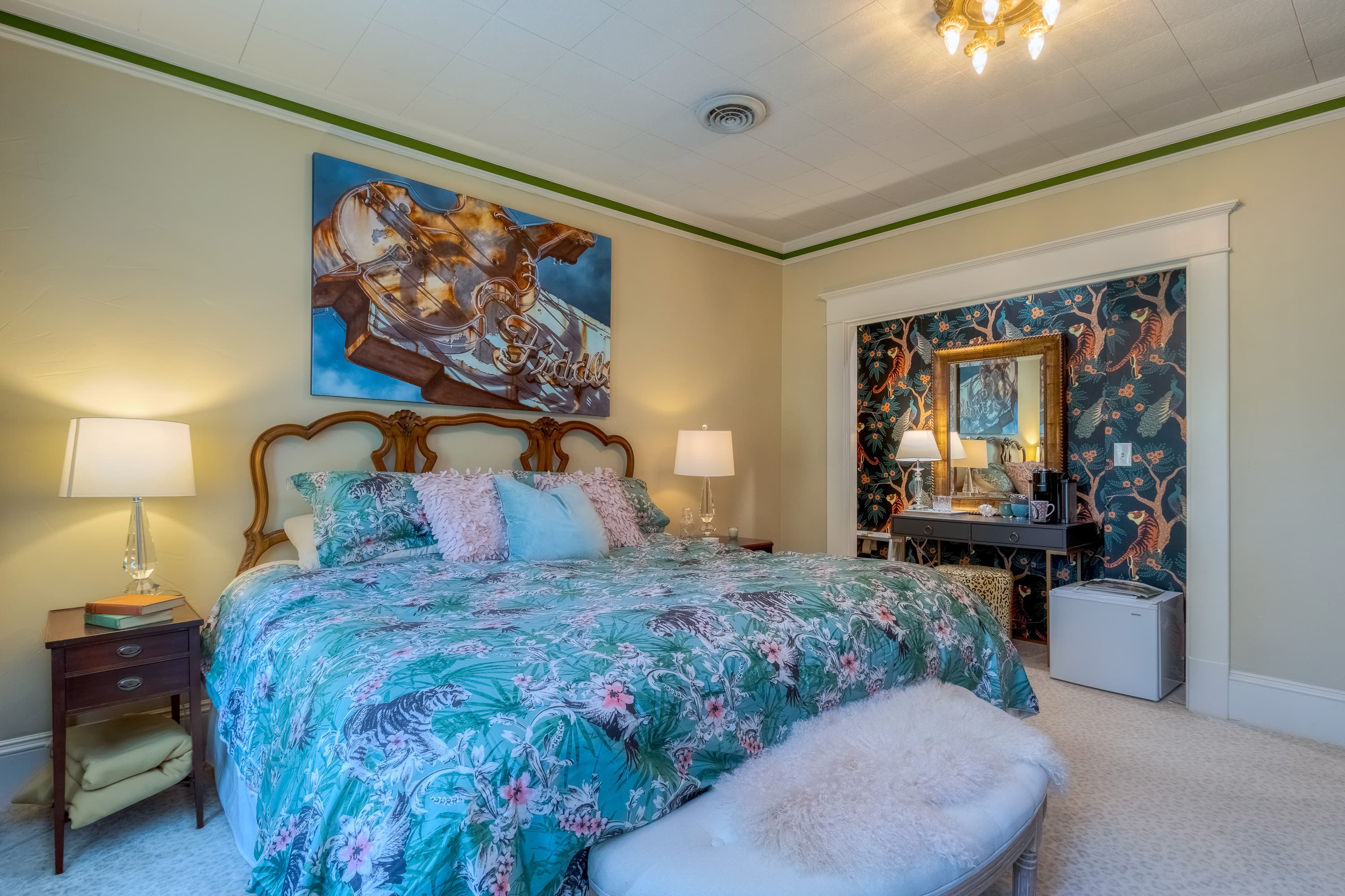A cozy bedroom featuring a floral-patterned bedspread, decorative wall art, and soft lighting.