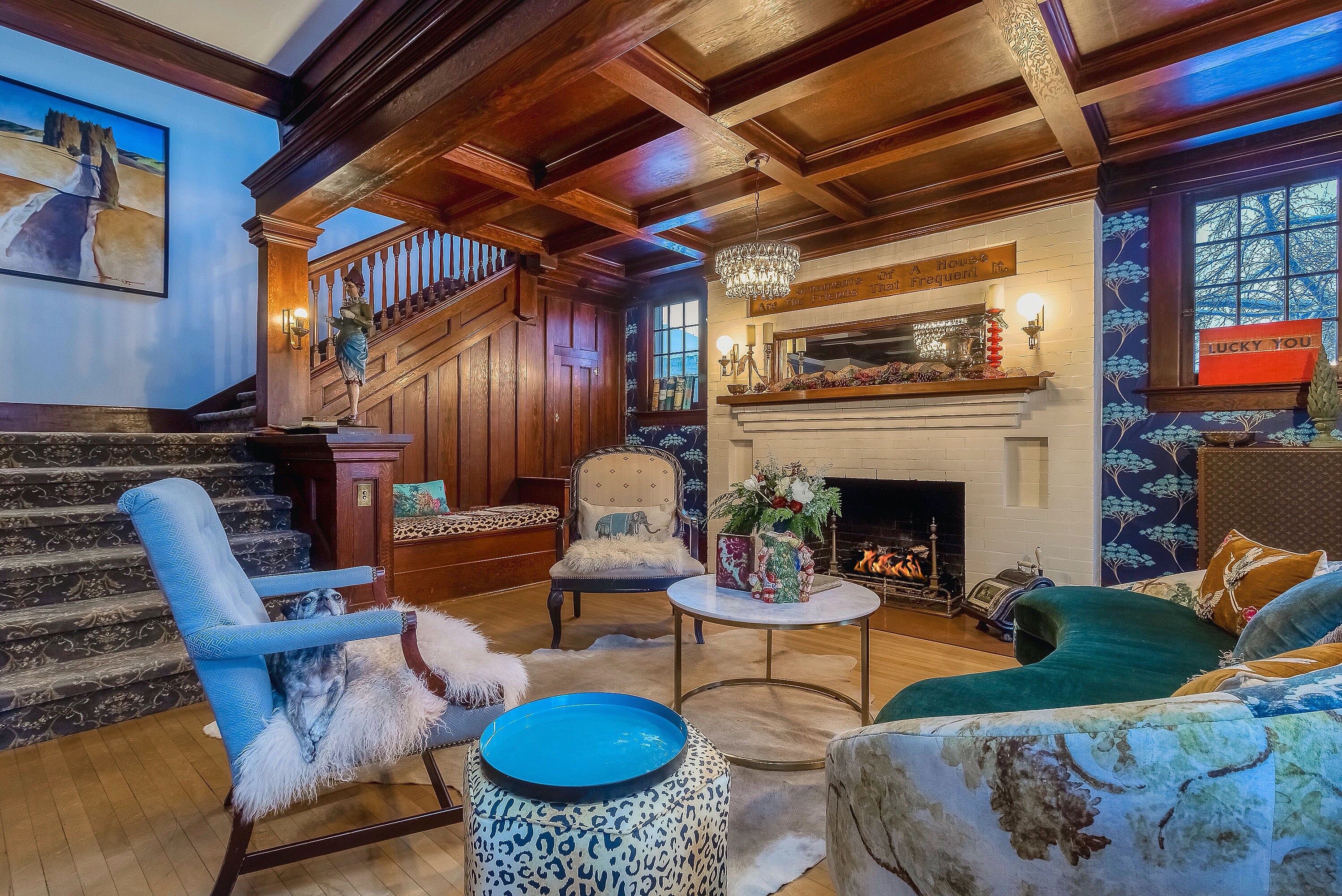 A cozy living room featuring a fireplace, decorative chairs, and an elegant wooden staircase.
