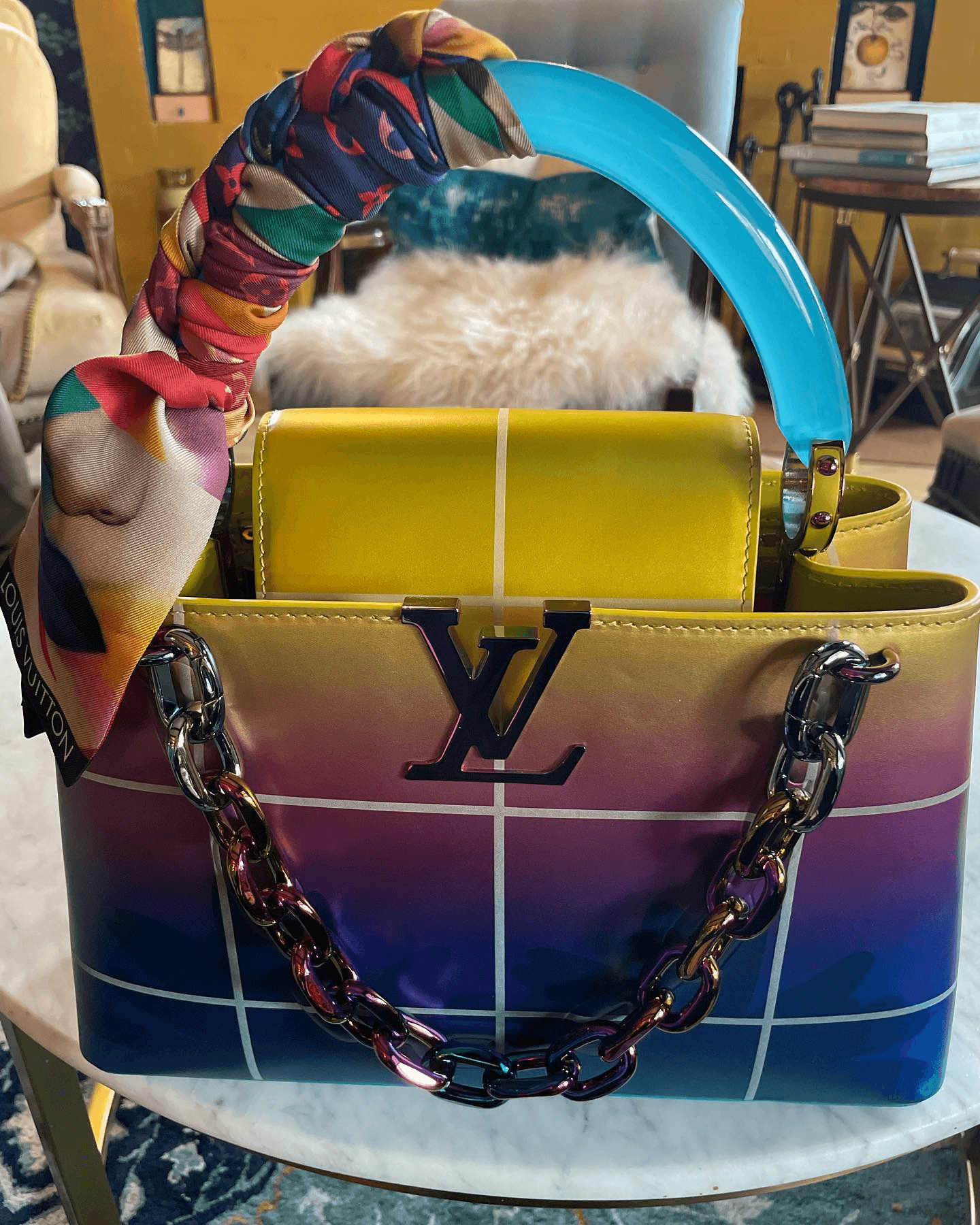 A stylish handbag with a colorful gradient design and an embellished handle.